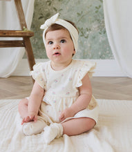 Load image into Gallery viewer, Baby in a white dress sitting on a blanket with a floral backdrop