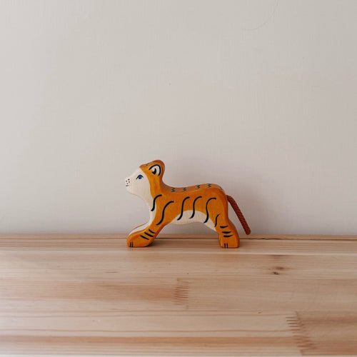 Wooden tiger toy on a wooden surface with a plain background