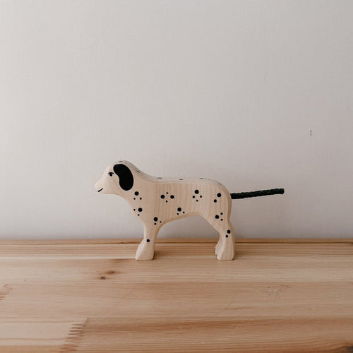 Wooden dog toy with black spots on a wooden surface
