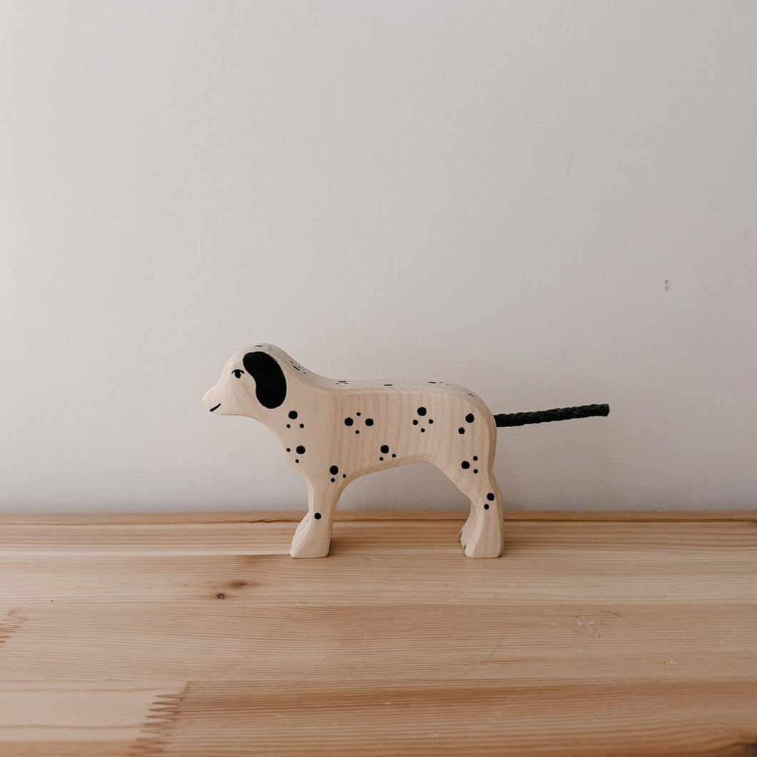 Wooden dog toy with black spots on a wooden surface