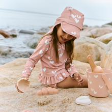 將圖片載入圖庫檢視器 Child in pink heart-patterned outfit playing on a rocky beach.
