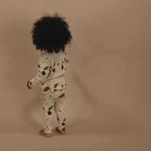 Load image into Gallery viewer, Child wearing a patterned outfit on a beige background
