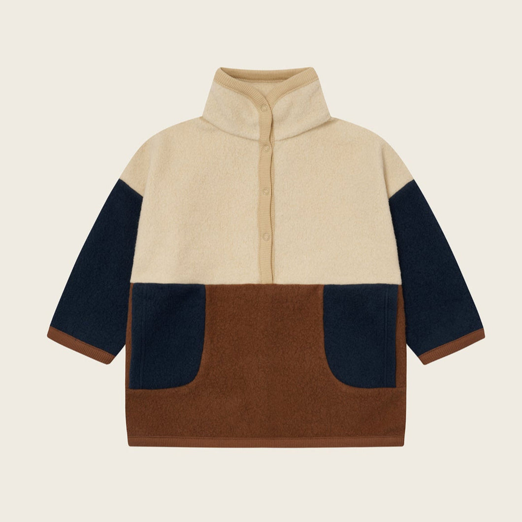 Color-blocked sweater with beige, navy, and brown sections on a light beige background