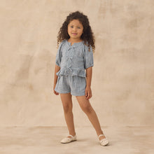 Load image into Gallery viewer, Young girl wearing a blue checkered outfit on a beige background
