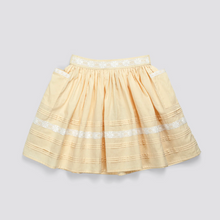 Load image into Gallery viewer, A light beige pleated skirt with white embroidered horizontal stripes and a matching white embroidered waistband, shown flat on a light gray background.
