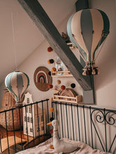 Load image into Gallery viewer, Children's room with hot air balloon decorations and toys on a bed.
